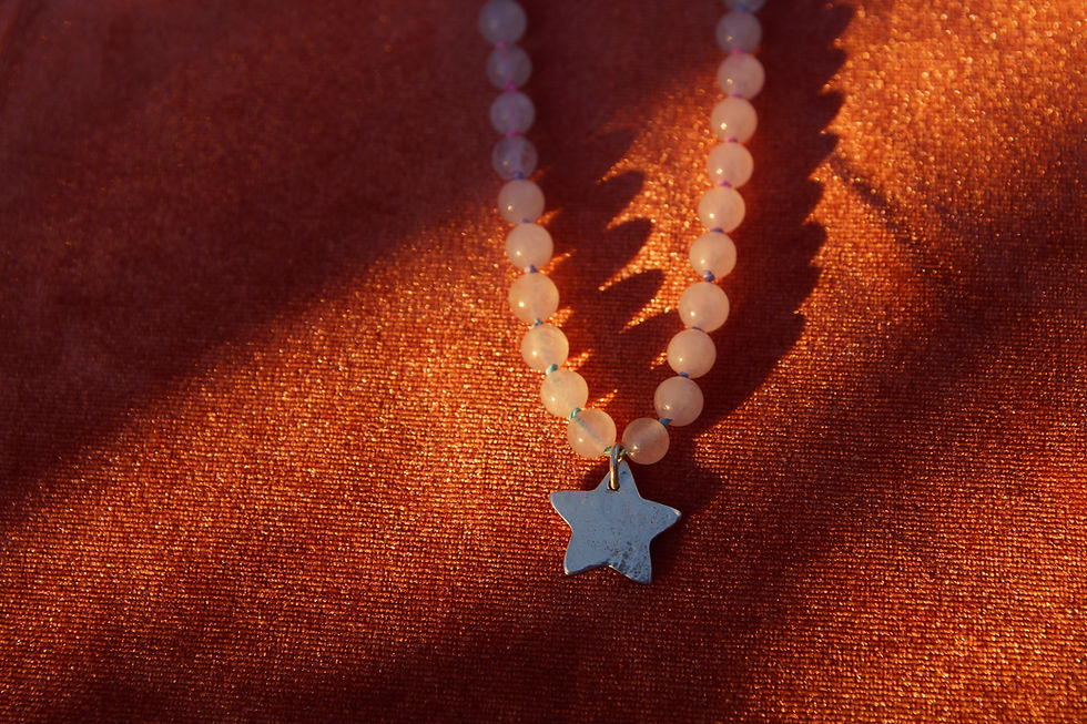 Beaded star necklace with light pink stones on a warm textured surface