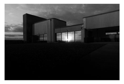 Black and white photograph of Aberavon.  Building at low light.  the sun causes the building's window to glow. 