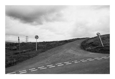 Black and white photograph showing a road junction in the valleys.  The word 'Butty' is painted on the road.