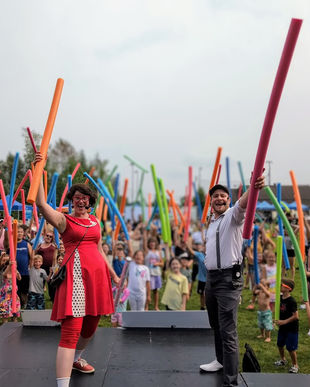 Animateur sur une scène devant un public tenant des nouille a piscine