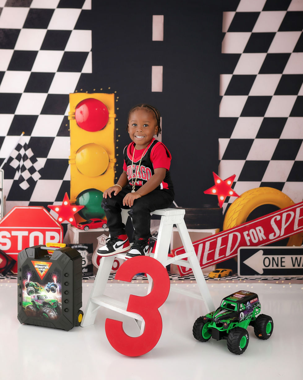 Race car photography backdrop for boys with checkered patterns, traffic lights, stop signs, toy cars, and Route 66 racing decor – ideal for milestone portraits