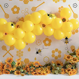 Bee-themed cake smash backdrop with yellow balloons, sunflowers, honeycomb prints, and cartoon bees – ideal for spring first birthday photography