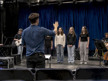 Conductor leading youth theatre click-track rehearsal