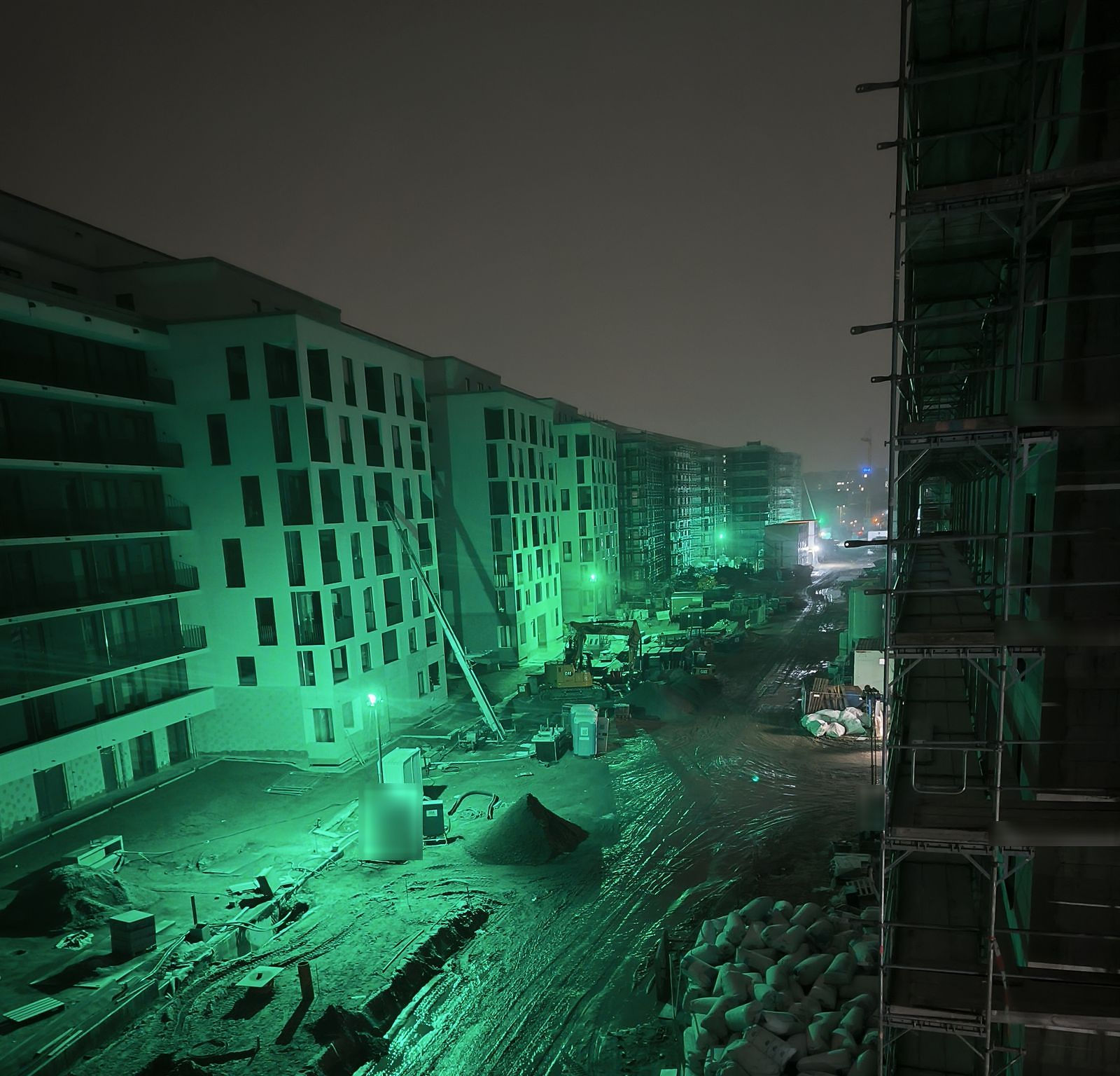 Baustelle in einem neuen Wohnquartier bei Nacht, beleuchtet von Baustrahlern