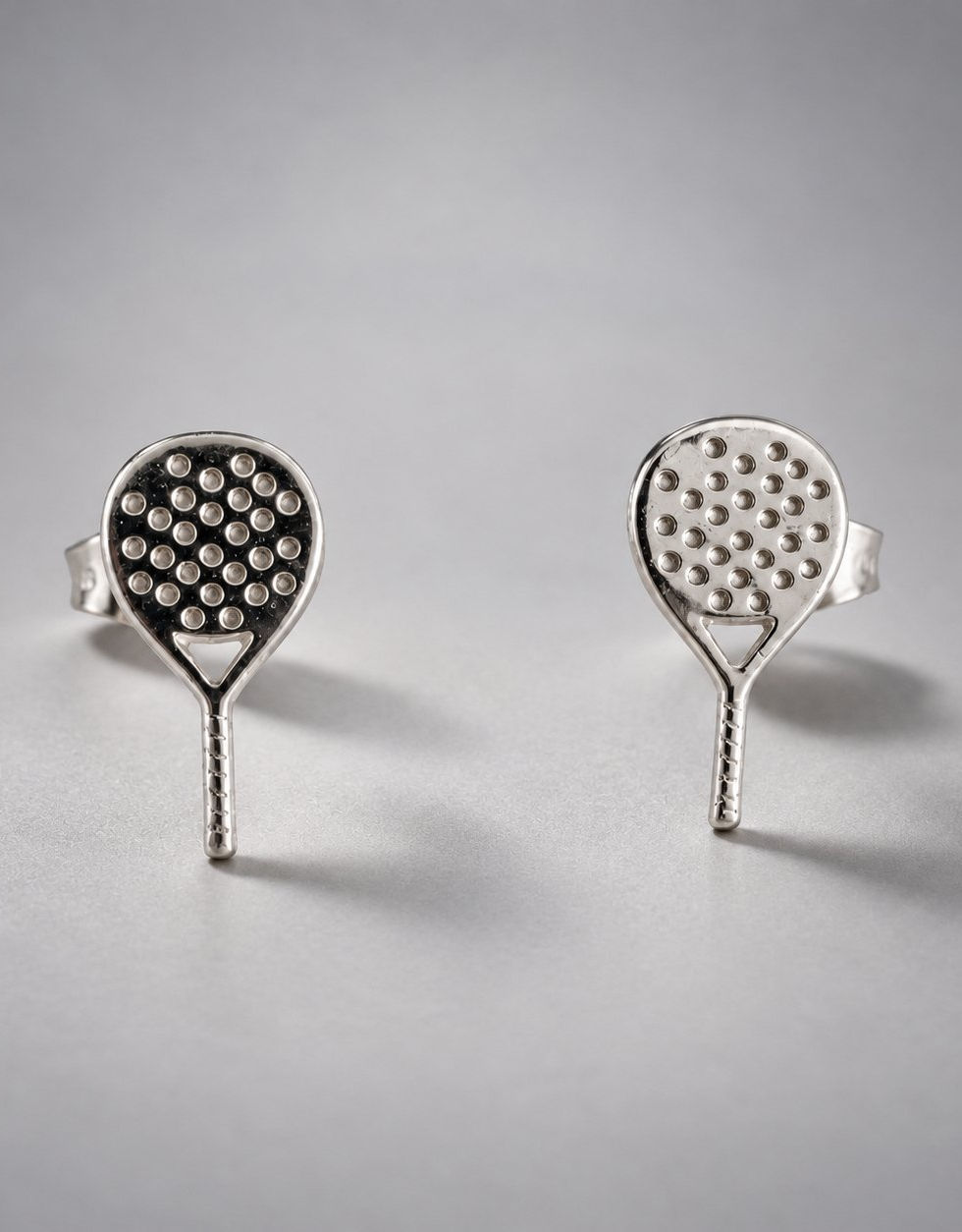 PÁDEL LOVER ARETES BROQUEL sobre fondo gris degradado.