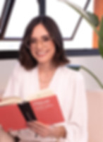 psicóloga Ana Luísa sentada segurando um livro e sorrindo