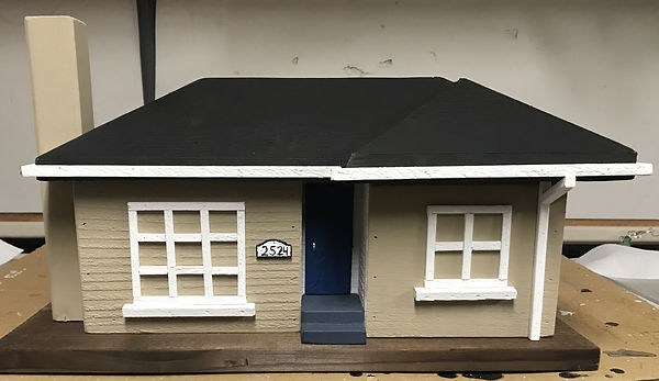 A beige birdhouse designed to look like the house in the previous image.