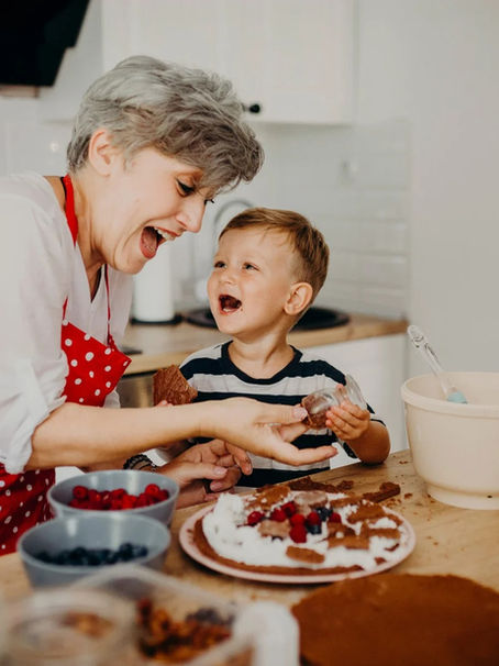 Grandmother and grandson smiling as they sit together, recording stories using StoriedLife while baking — capturing family memories across generations.