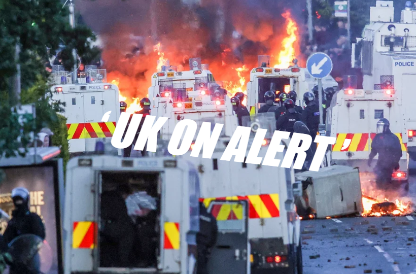 Police vans and riot officers face huge flames and smoke in a city street; UK ON ALERT text over the scene.