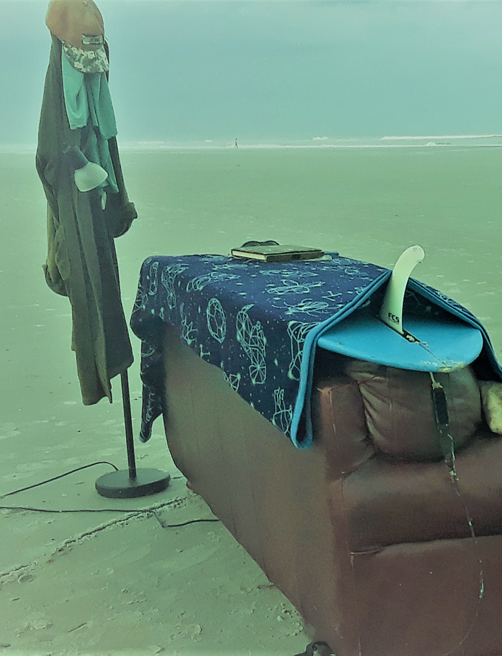 Sofa and surfboard fin on a sandbar beach, text: SANDBAR SOFA SURFERS