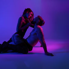 a coloured gel image of a tattooed couples boudoir