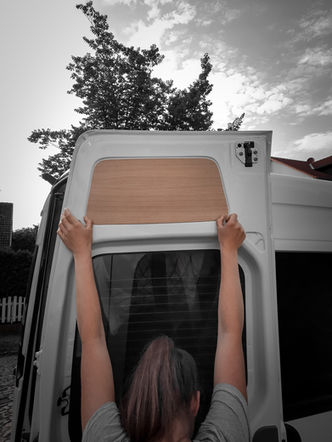 A woman holds a wooden board made of oak to a vehicle door