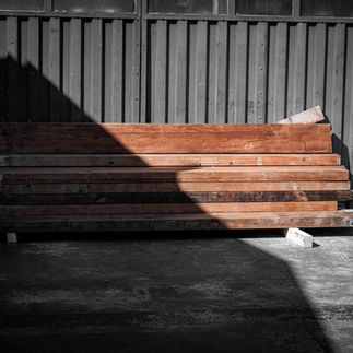 Wooden beams are stacked in front of a wall