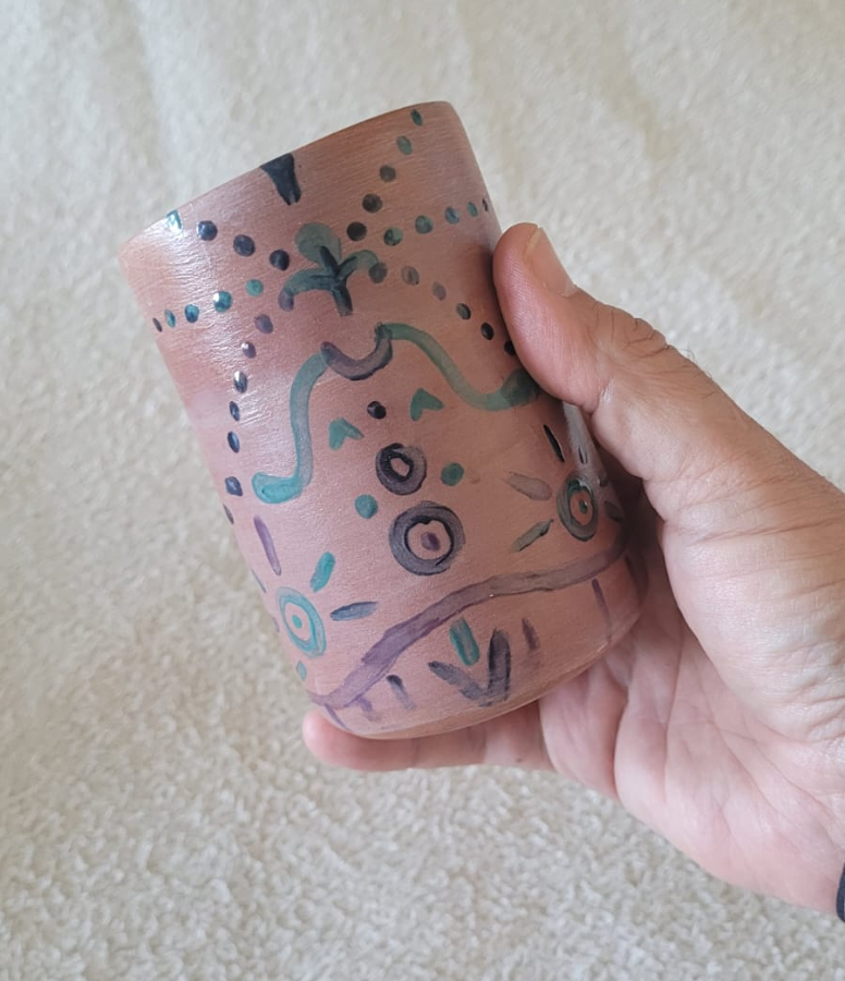 Mano de mujer sujetando un vaso cerámico sobre toalla, punto de partida para la mejora visual con herramientas de IA para emprendedoras.