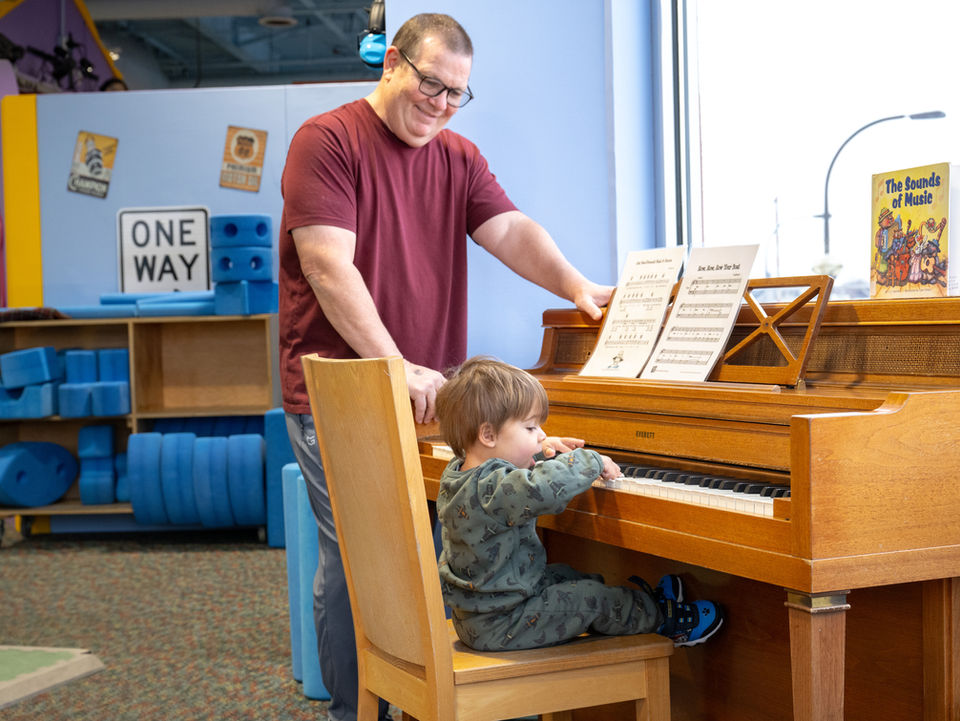 parent and child at piano inside tree house display
