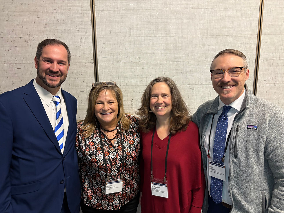 Four people smiling together, standing for a photo at an event.