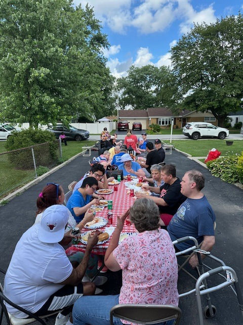 Group of people dining outdoors at Park Lawn, enjoying a meal together.