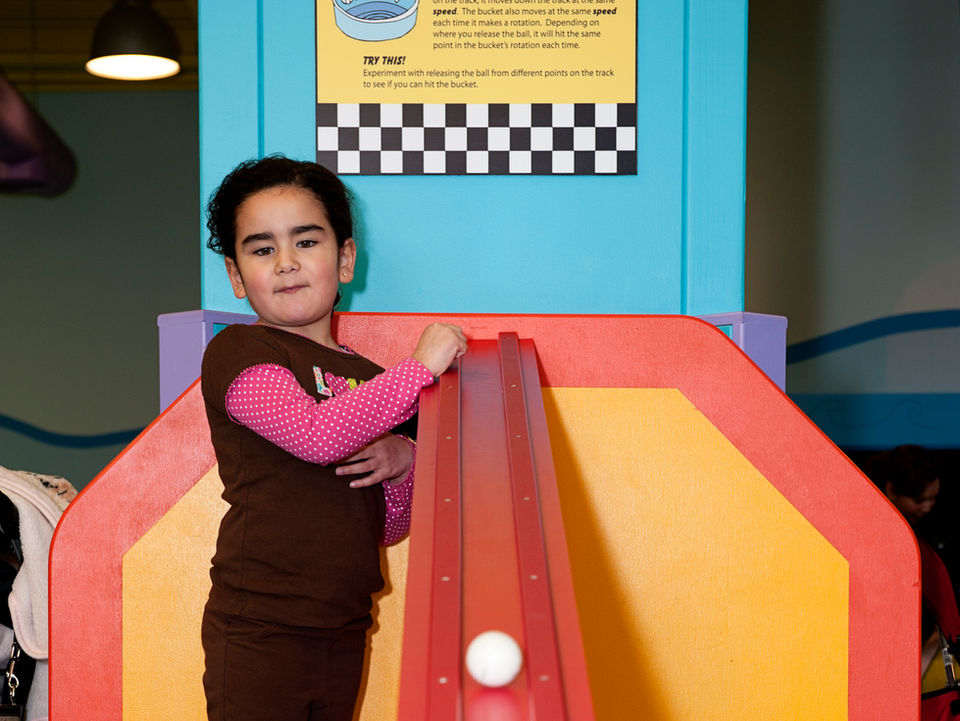 girl rolling ball down exhibit slide