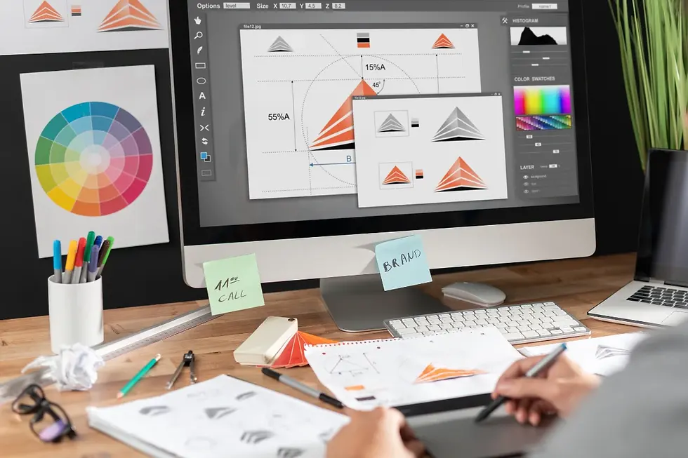 Designer working at a desk with graphic software on a computer. Geometry designs on screen. Color wheel and sticky notes visible. Creative mood.
