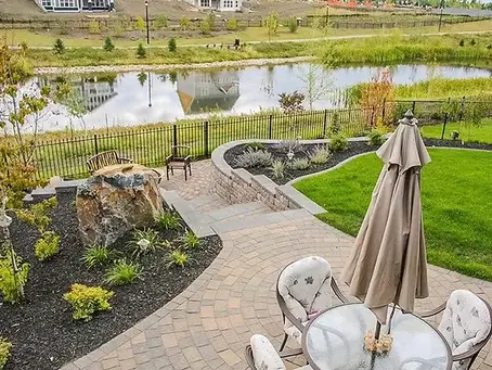 Beautifully landscaped backyard in Edmonton featuring lush green lawn, vibrant flower beds, and a modern stone patio, designed by Paradise Pines Landscaping.