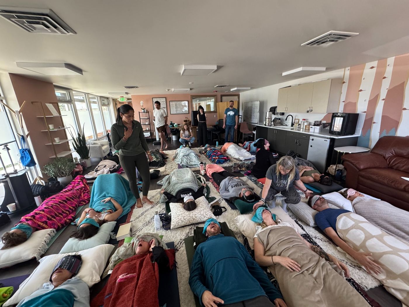 A group participating in conscious breathwork with soft eye coverings and blankets
