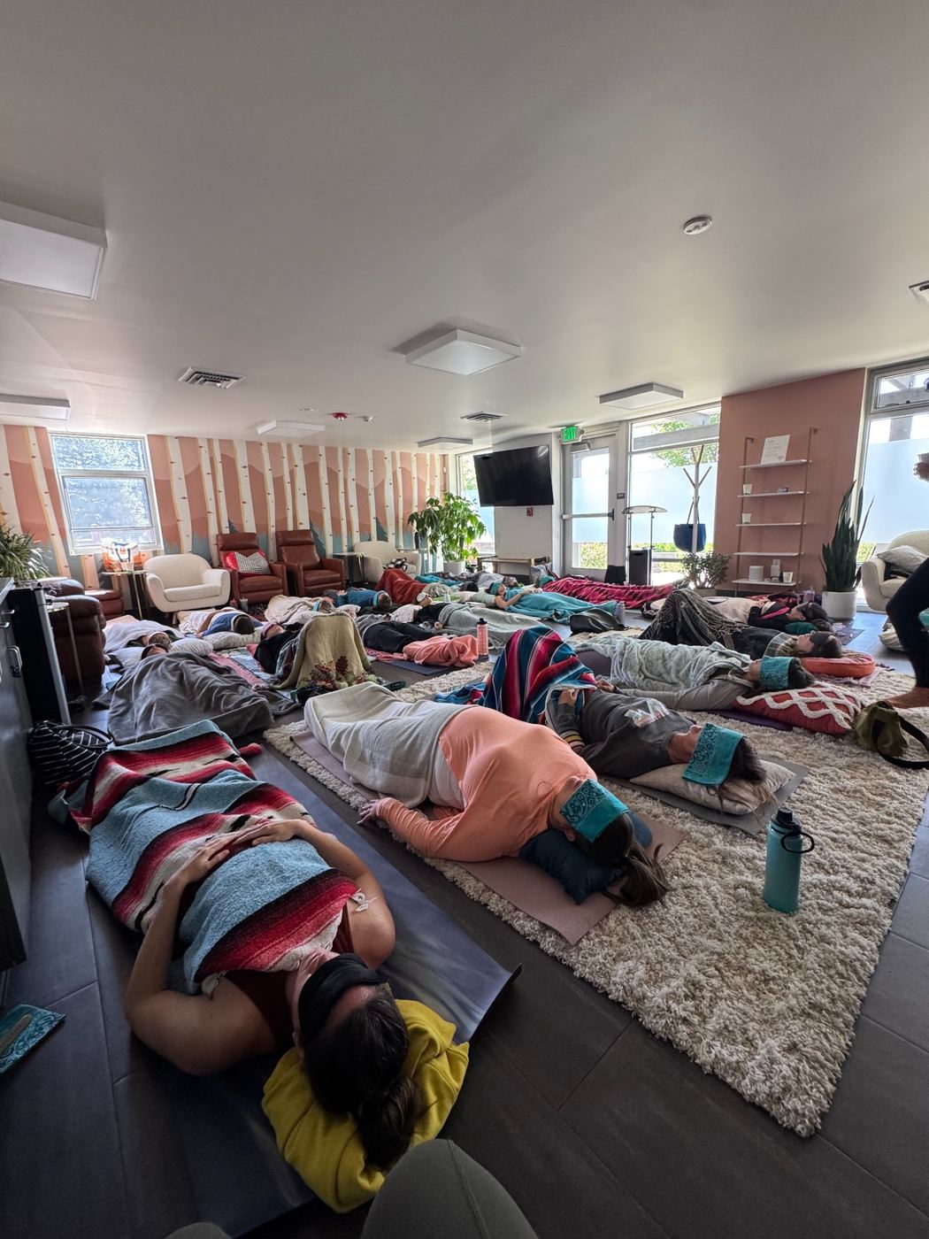People resting on mats and blankets during a guided group breathwork practice