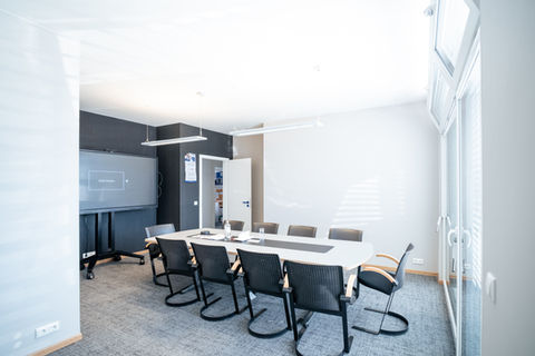 Modernes Besprechungszimmer mit großem Tisch und Bildschirm