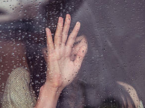 Woman crying through a rain-soaked window