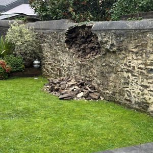 Effondrement partiel du mur en pierre avec chute des pierres au pied de l’ouvrage.