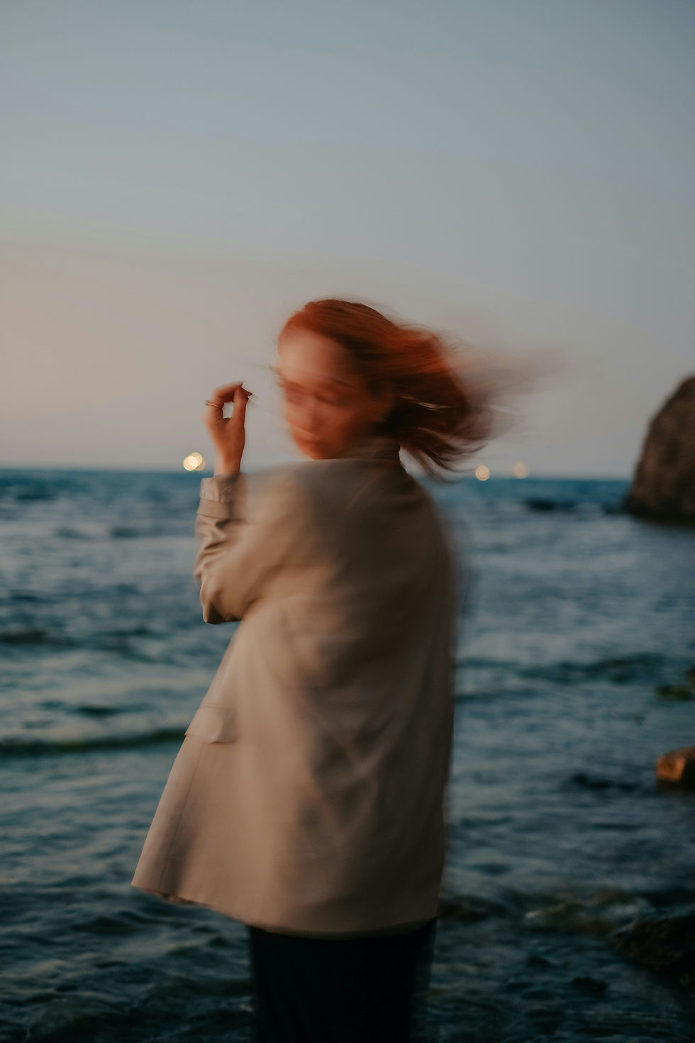 Women at sunset at the beach with hair and faced blurred in wind
