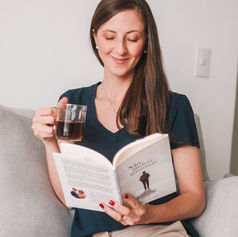 Mulher segurando uma xícara de café e lendo um livro.