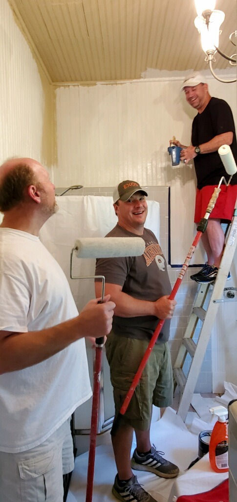 Three men painting a room.