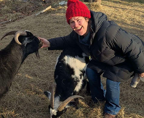Christy is smiling with two goats, goat yoga in Claremont, New Hampshire
