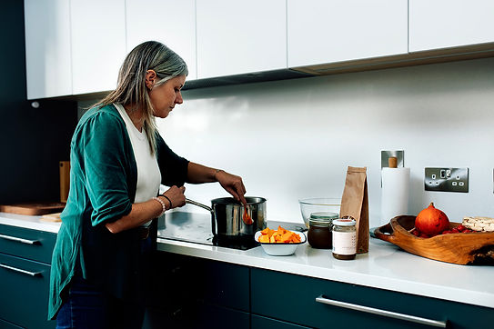 Ceara cooking at a baby shower. She is stirring a pot, about to add in more chopped butternut squash.