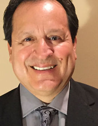 Professional headshot of Raul Saldivar, Board Chair of 3DA, wearing a suit and tie and smiling against a neutral background.