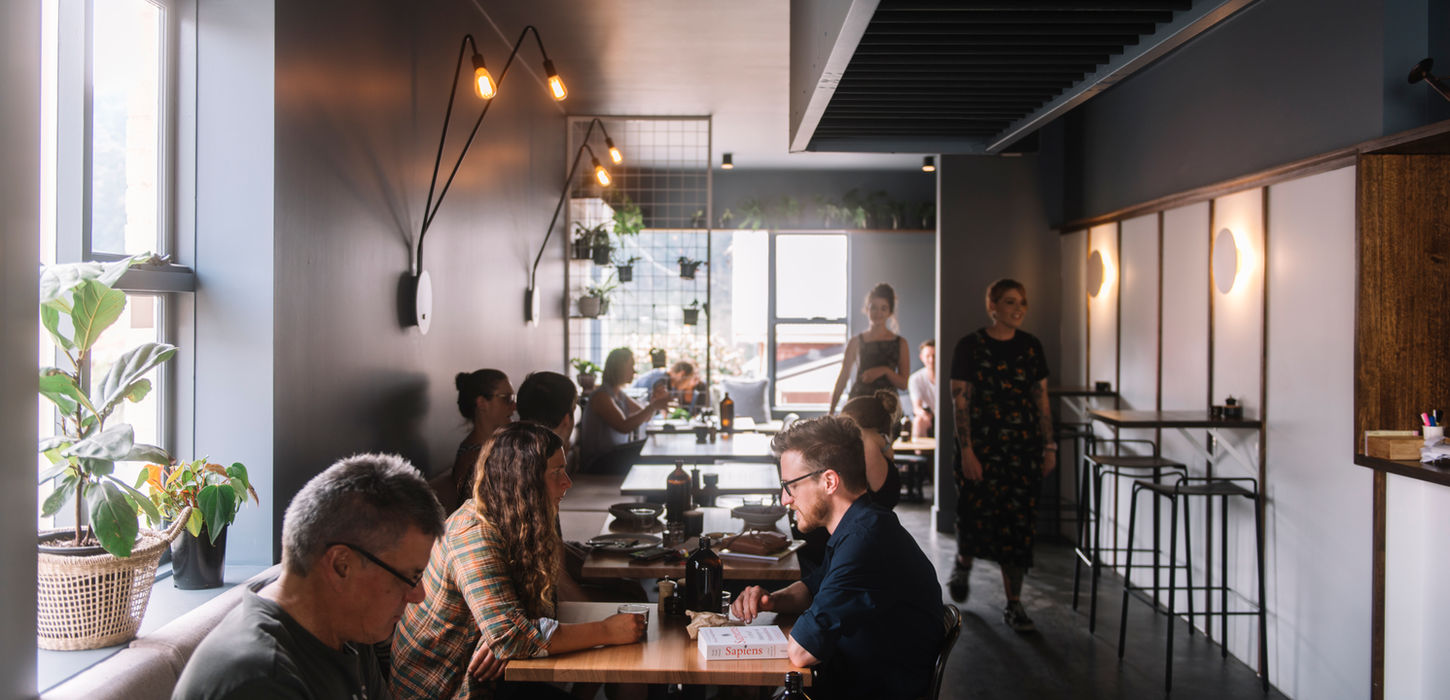 Café space at Bear With Me in South Hobart, featuring retained original French panelling under exterior windows, complemented by contemporary contrast panelling within the interior