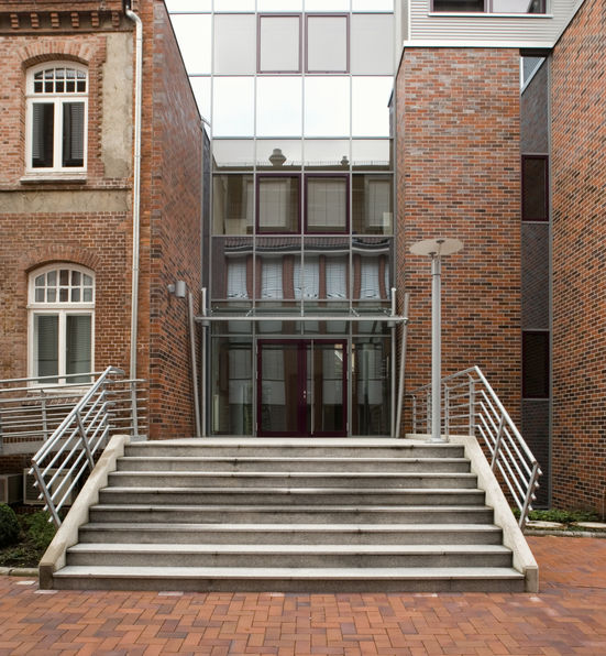 Treppenhaus aus Stahl und Glas verbindet Bestand mit Neubau