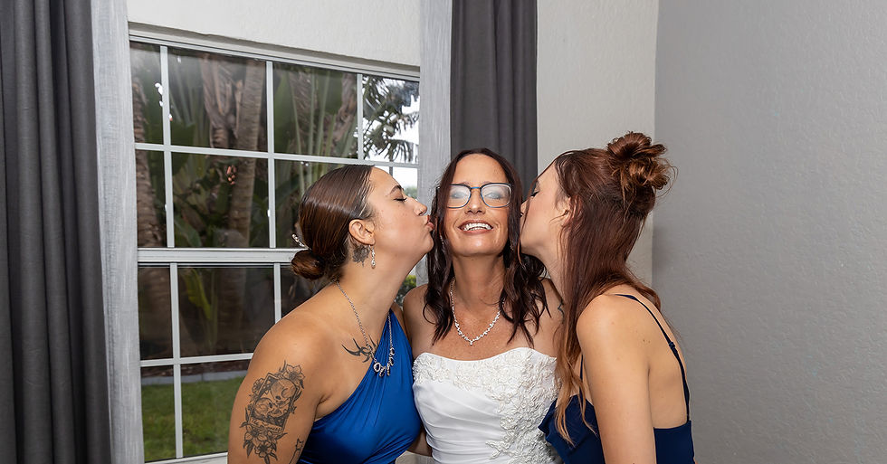 Bride smiling as her two daughters kiss her cheeks before her Cocoa Beach wedding