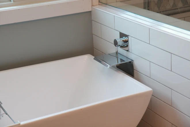 A close up of a waterfall-style bathtub faucet