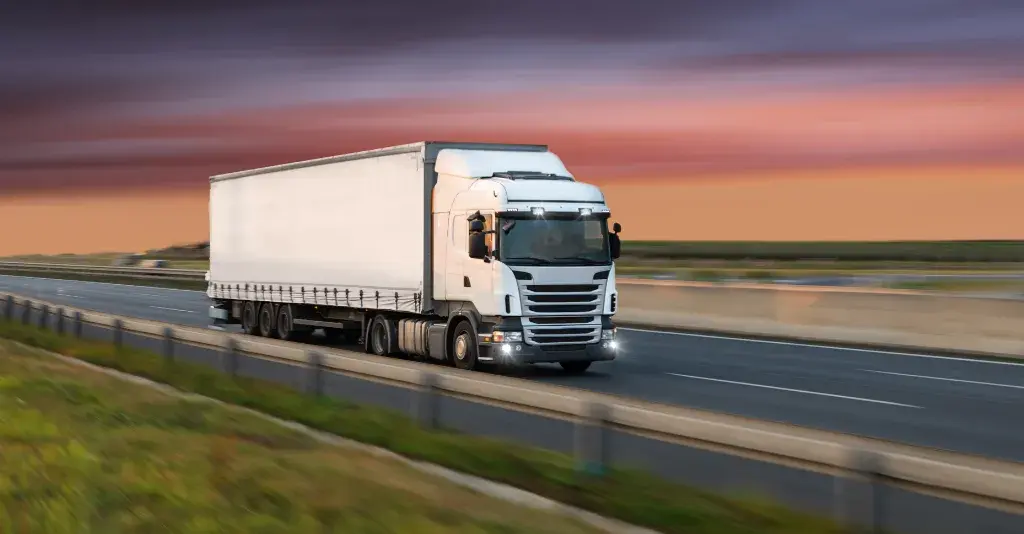 White freight truck driving on highway at sunset in Andalusia, Alabama – Tiger Freight road shipping service


