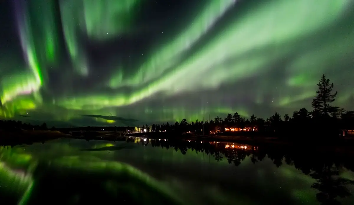 Green Northern Lights reflecting over a Finnish lake at night.