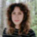 A white woman with long brown curly hair and a black and white striped shirt.
