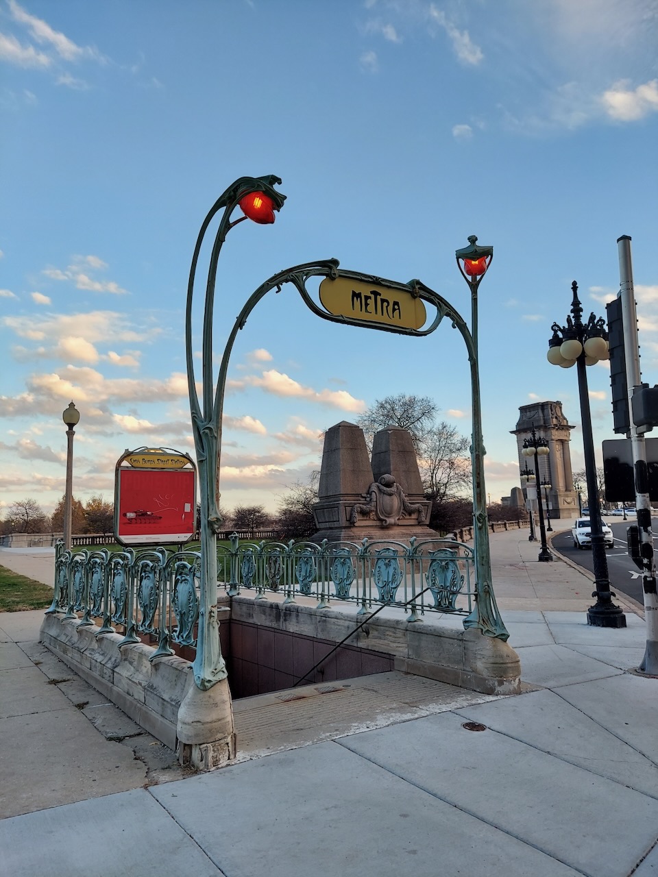 A Metra entrance with ornate metalwork and red lamps.