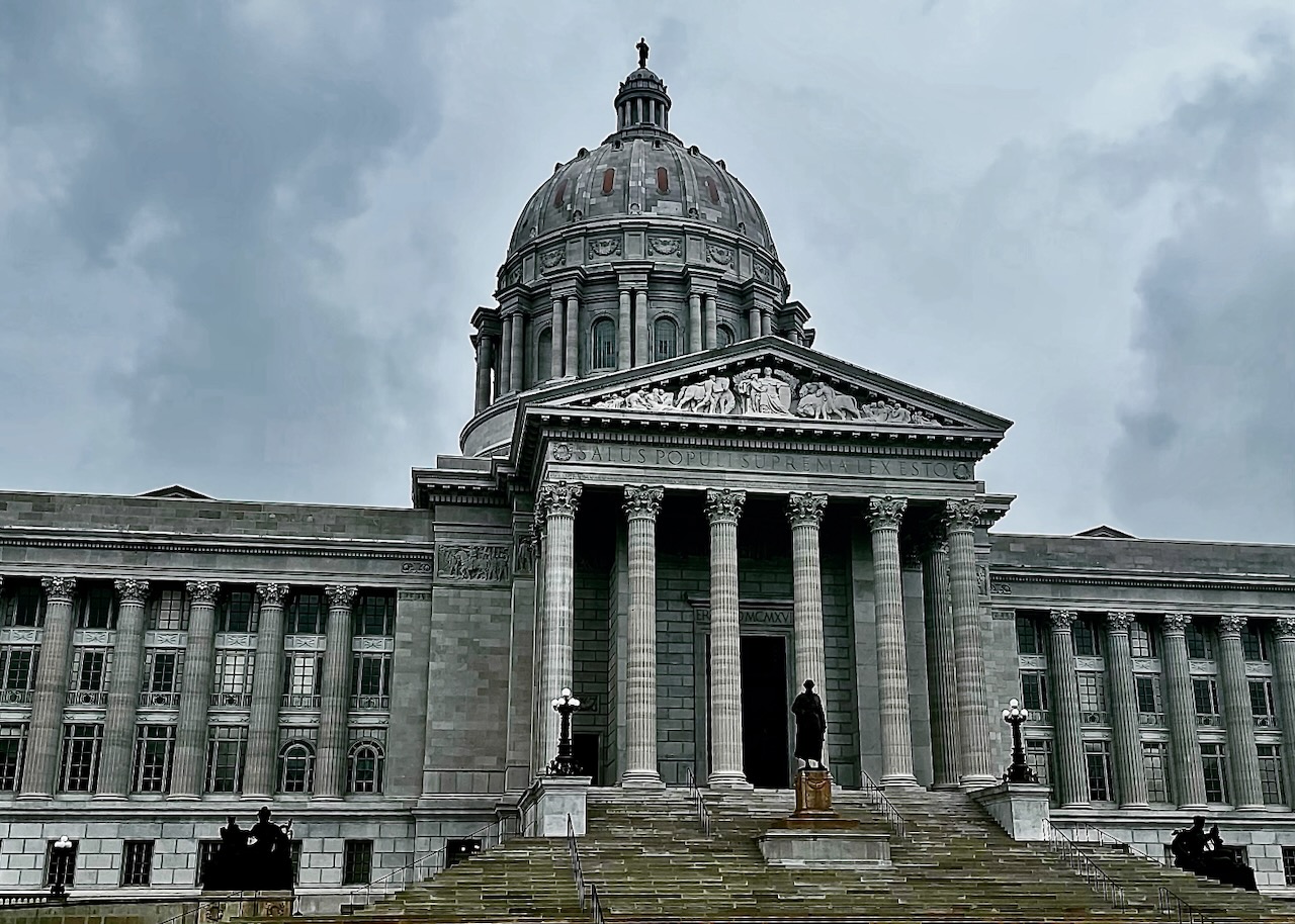 A domed civic building with columns under gray clouds.