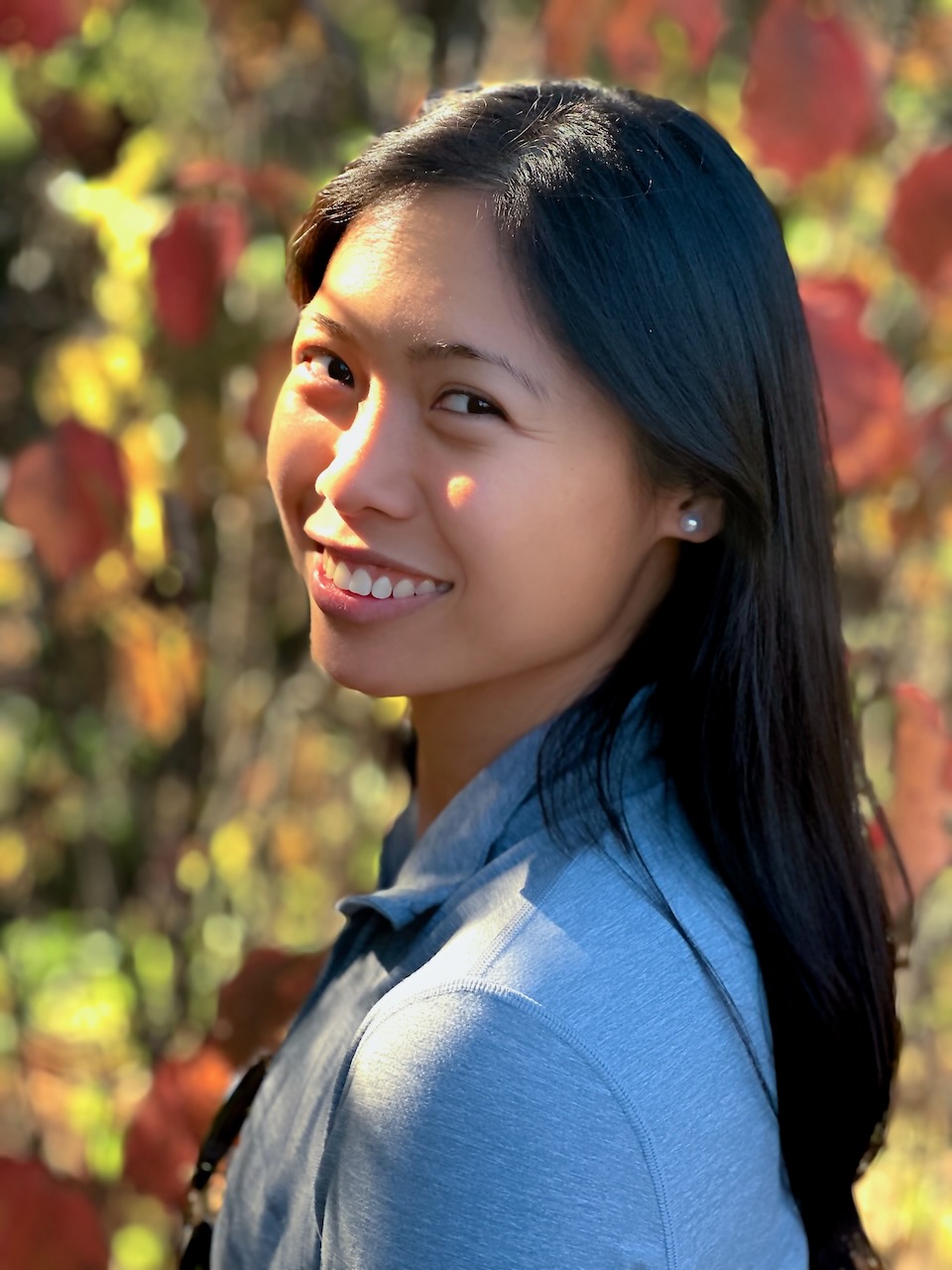 A portrait in front of softly blurred autumn leaves.