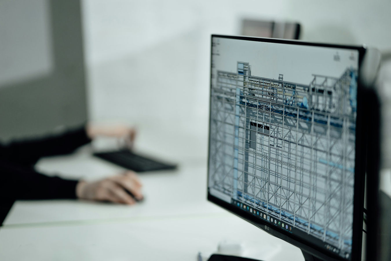 A designer working at a computer workstation with architectural drawings and digital modeling tools.