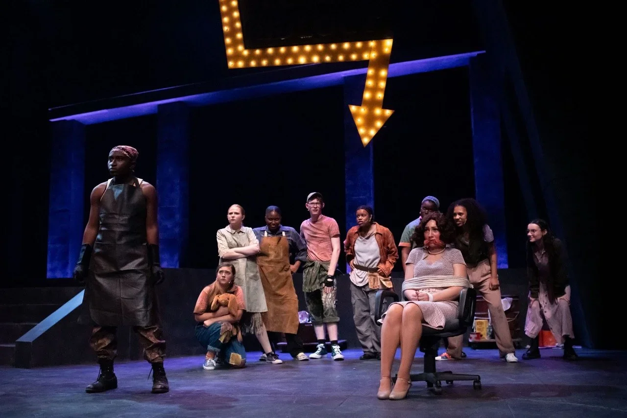 Scene of Urinetown with the civic-industrial set framing the cast.