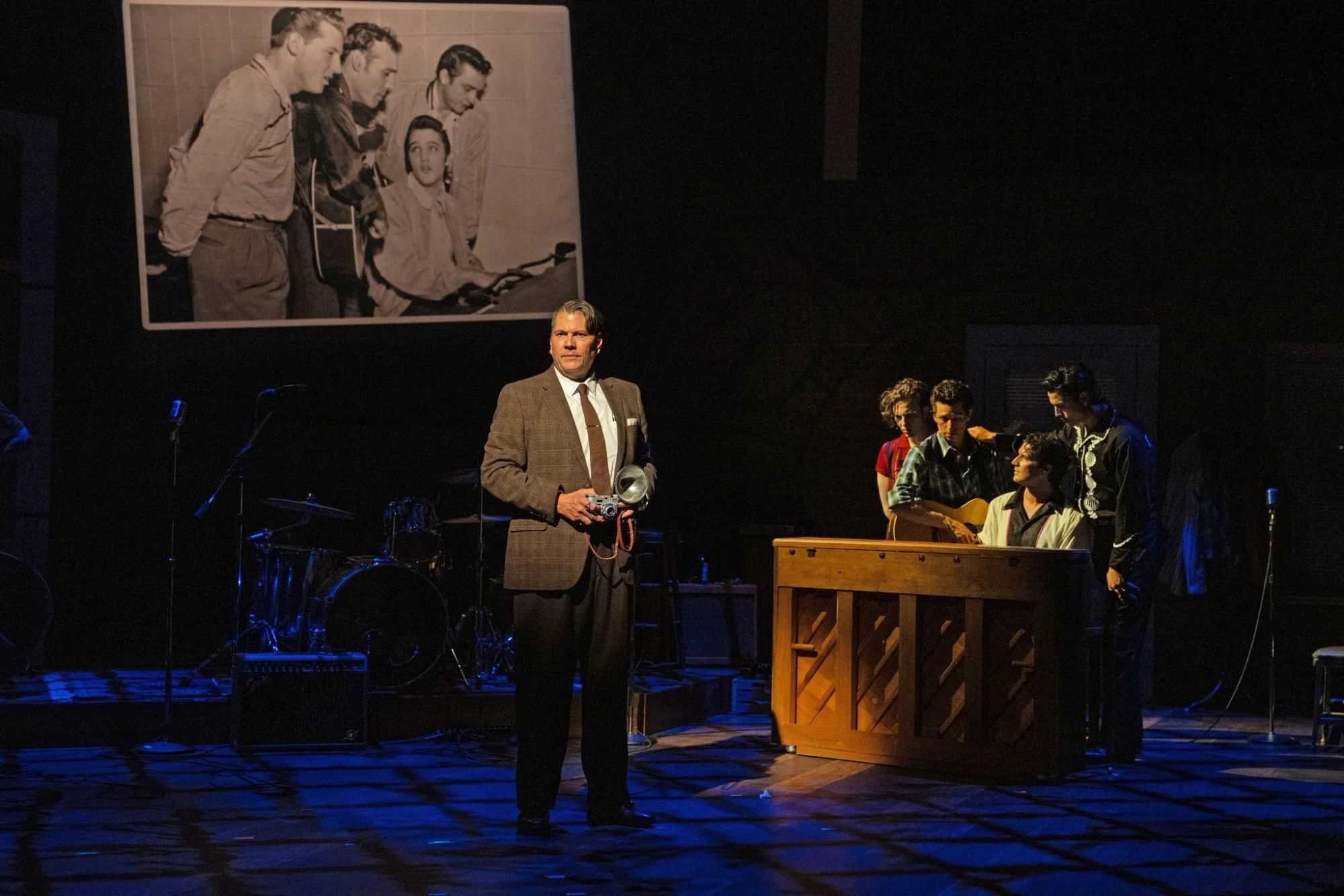 Band-centered stage composition with warm practical lighting in Million Dollar Quartet.