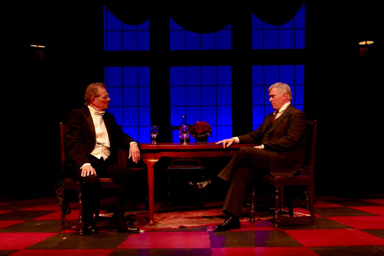 Two actors seated across the dining table in An Inspector Calls at Okoboji Summer Theatre.