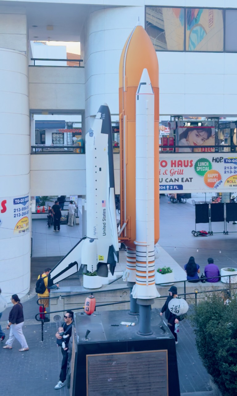 A model space shuttle and rocket boosters in an open plaza.